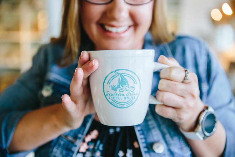 Woman holding southern grind coffee cup